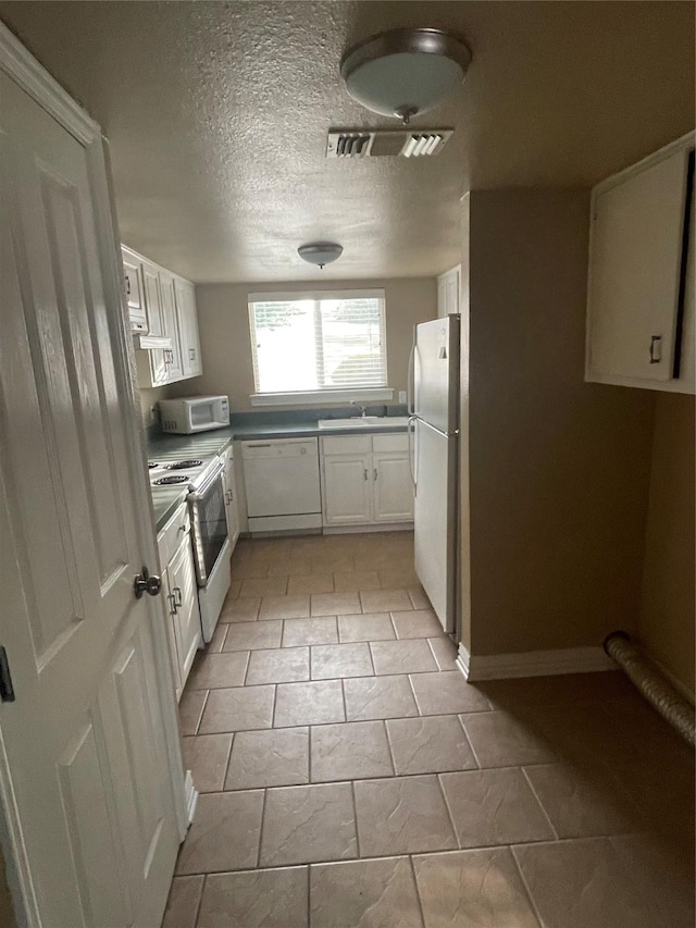 kitchen featuring a textured ceiling, sink, white cabinets, and white appliances