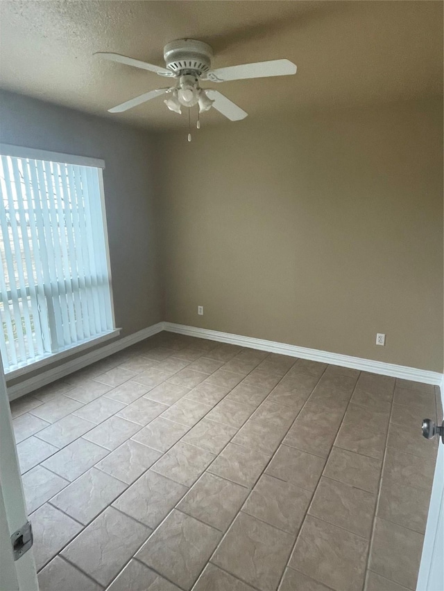 empty room featuring ceiling fan, light tile patterned floors, and a textured ceiling