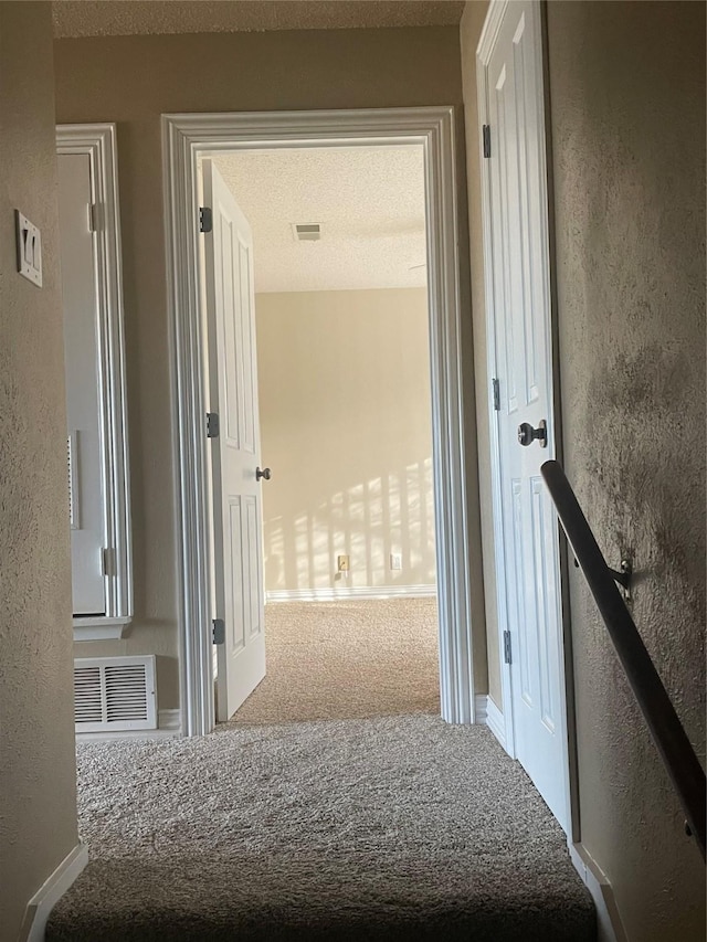 corridor featuring carpet and a textured ceiling