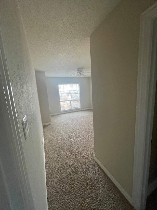 hall featuring carpet floors and a textured ceiling