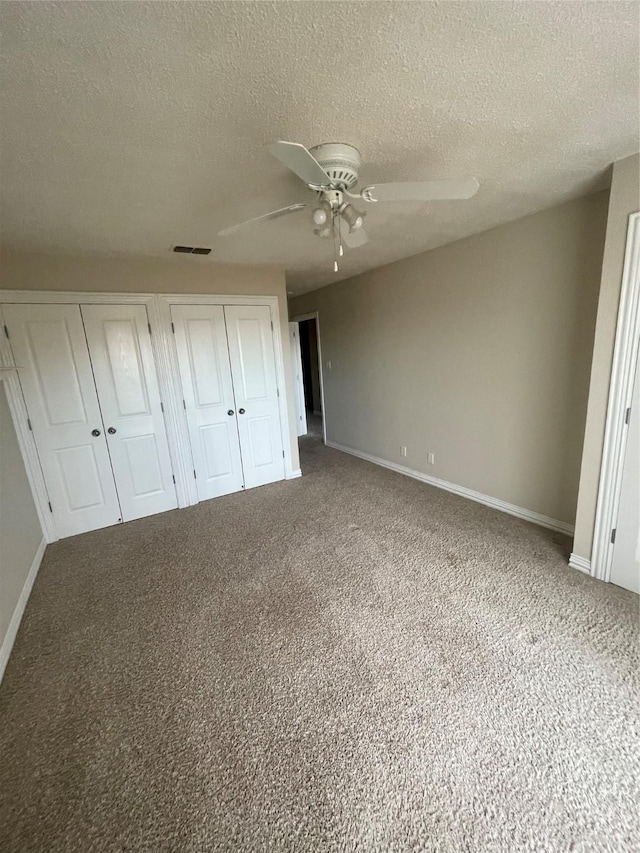 unfurnished bedroom with a textured ceiling, carpet floors, ceiling fan, and multiple closets