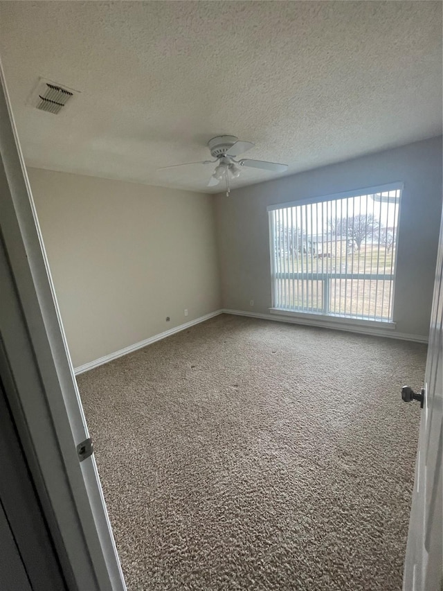 empty room with carpet, ceiling fan, and a textured ceiling