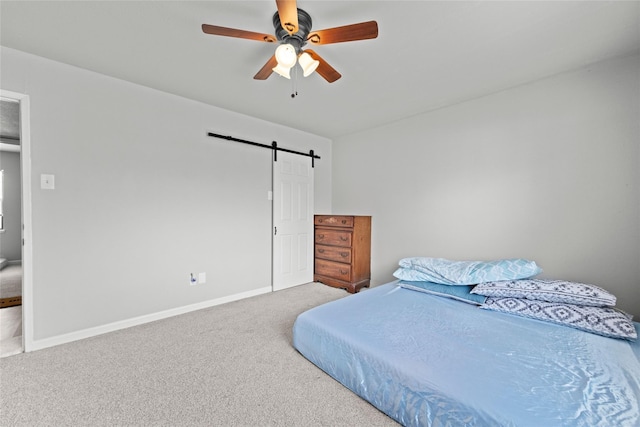 bedroom with ceiling fan, carpet flooring, and a barn door