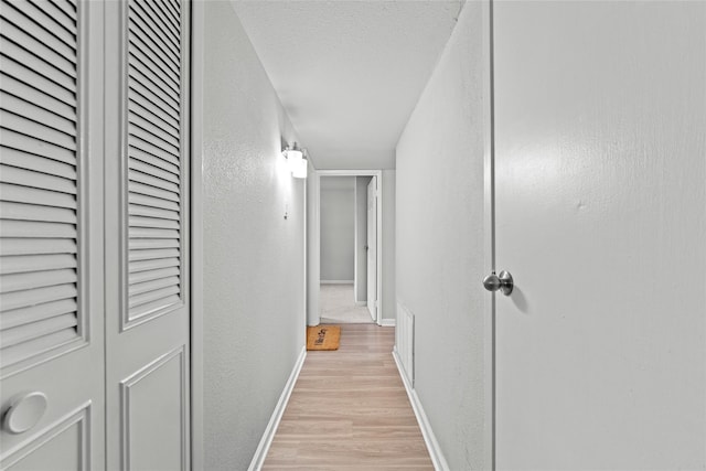 hallway featuring light hardwood / wood-style floors and a textured ceiling