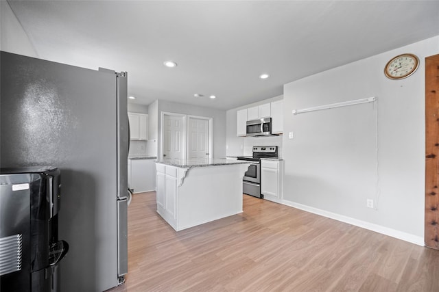 kitchen featuring light stone countertops, appliances with stainless steel finishes, a center island, and white cabinets