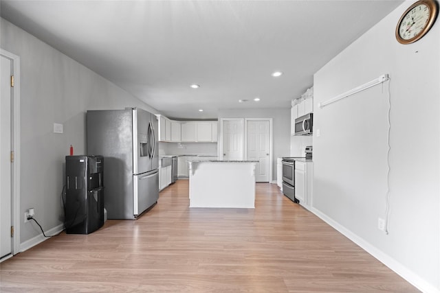 kitchen featuring stainless steel appliances, a center island, white cabinets, and light wood-type flooring