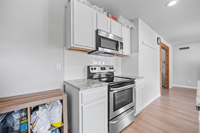 kitchen with white cabinetry, appliances with stainless steel finishes, light wood-type flooring, and decorative backsplash