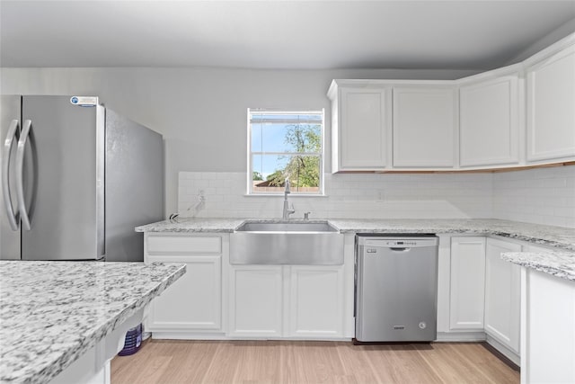 kitchen with appliances with stainless steel finishes, sink, light hardwood / wood-style flooring, and white cabinets