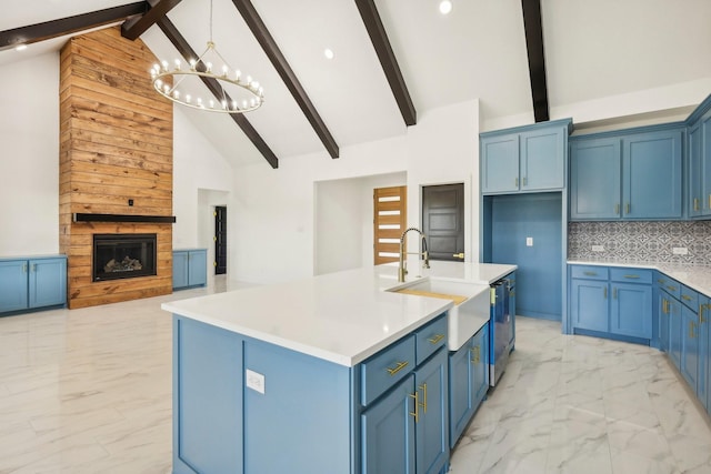 kitchen featuring a large fireplace, sink, a kitchen island with sink, and blue cabinetry