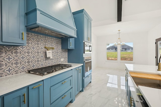 kitchen featuring appliances with stainless steel finishes, decorative light fixtures, decorative backsplash, custom range hood, and blue cabinetry