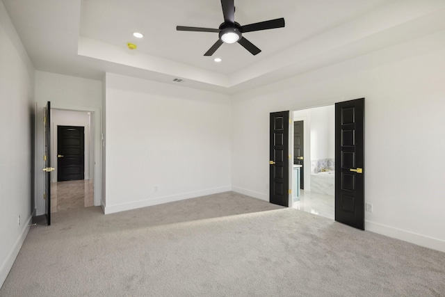 spare room featuring light colored carpet, ceiling fan, and a tray ceiling