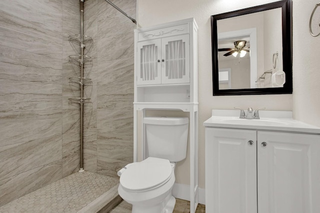 bathroom featuring vanity, ceiling fan, toilet, and a tile shower