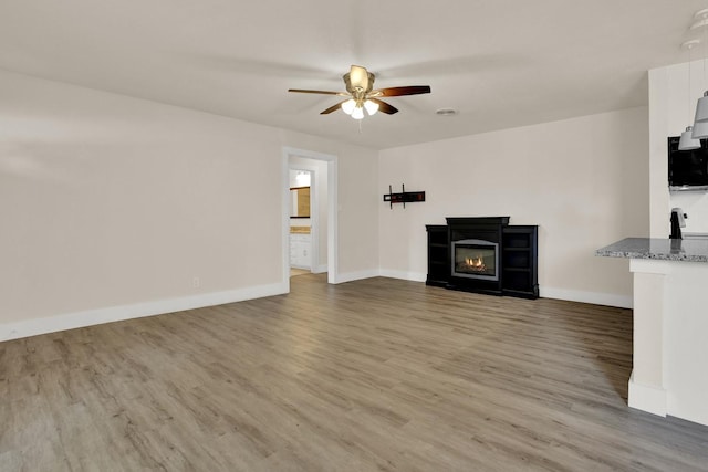 unfurnished living room with wood-type flooring and ceiling fan