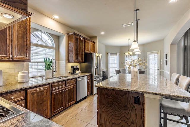 kitchen with sink, a kitchen bar, a center island, and appliances with stainless steel finishes