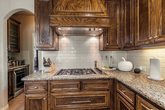 kitchen with wine cooler, dark brown cabinets, stainless steel gas cooktop, and custom range hood