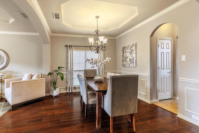 dining area with crown molding, a tray ceiling, and a notable chandelier