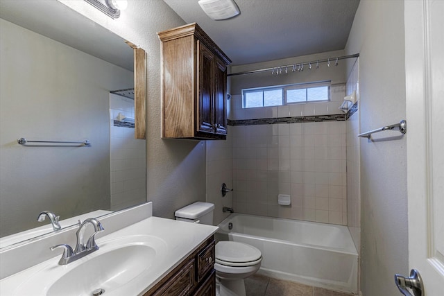 full bathroom featuring tile patterned flooring, vanity, a textured ceiling, tiled shower / bath, and toilet