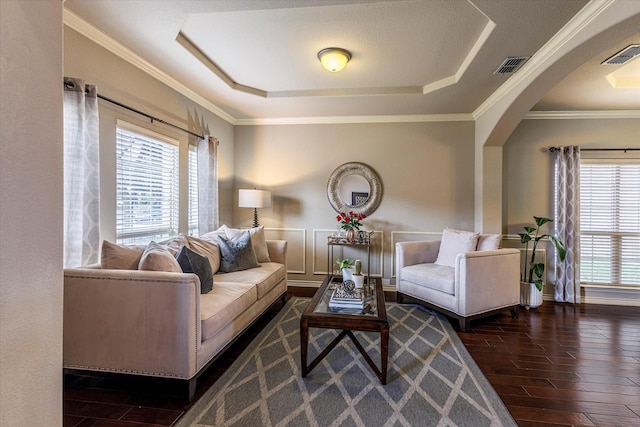 living room with a raised ceiling, crown molding, and dark wood-type flooring