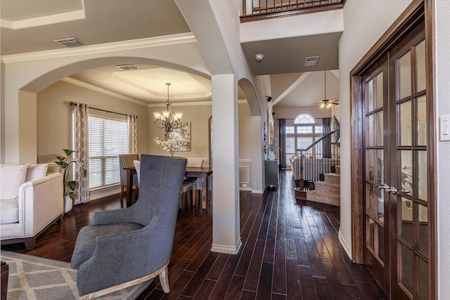 entrance foyer with ornamental molding, a healthy amount of sunlight, and dark hardwood / wood-style flooring