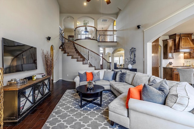 living room with ceiling fan, a towering ceiling, and dark hardwood / wood-style flooring