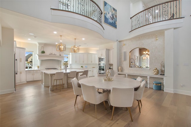 dining area featuring a high ceiling and light hardwood / wood-style flooring