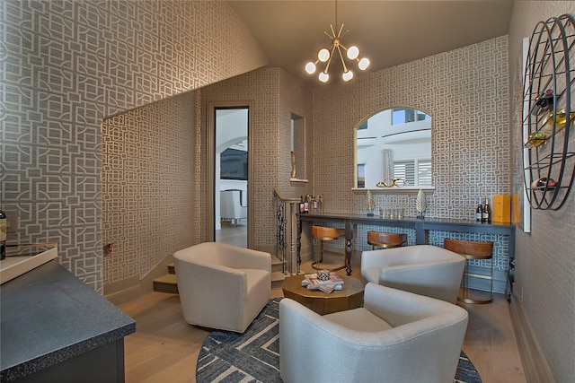 sitting room with vaulted ceiling, hardwood / wood-style floors, and a notable chandelier