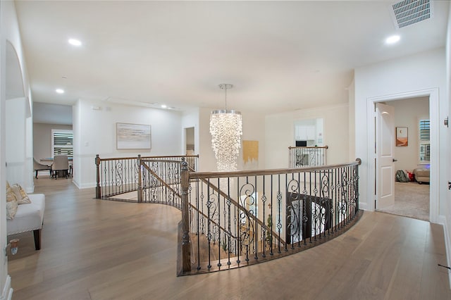 hallway with an inviting chandelier and wood-type flooring