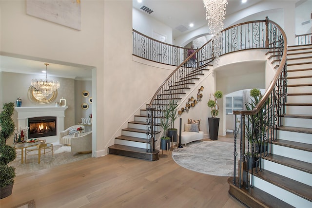 interior space with a notable chandelier, a towering ceiling, and light hardwood / wood-style floors