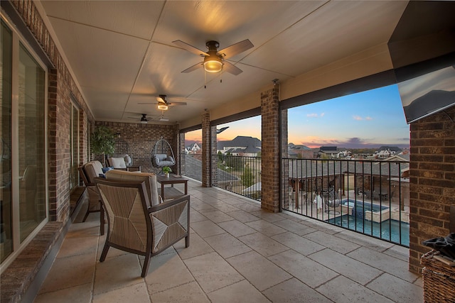 patio terrace at dusk featuring ceiling fan and a fenced in pool