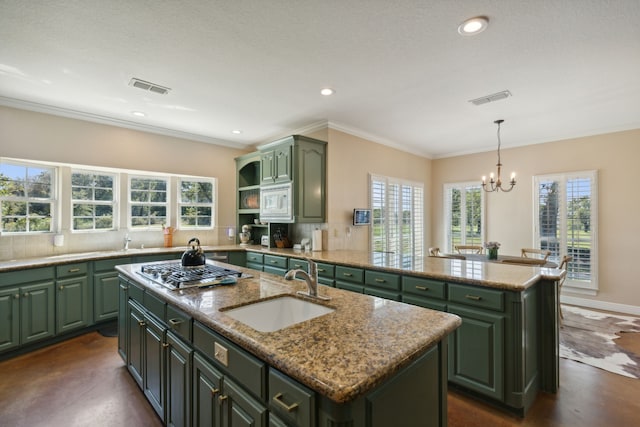 kitchen with an island with sink, sink, and green cabinetry