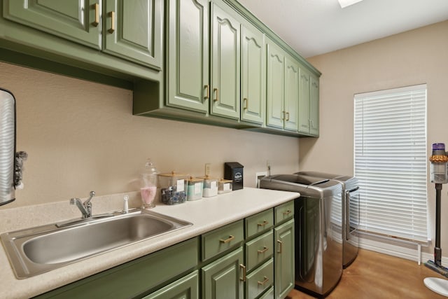 clothes washing area featuring independent washer and dryer, cabinets, sink, and light hardwood / wood-style flooring