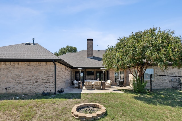 rear view of property featuring a lawn, a patio, and an outdoor living space with a fire pit