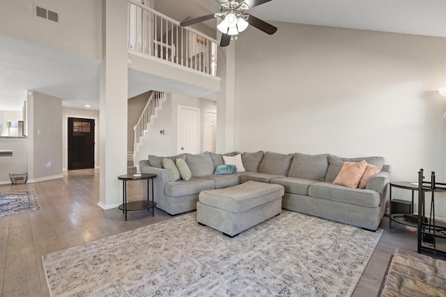 living room with ceiling fan, hardwood / wood-style floors, and a towering ceiling