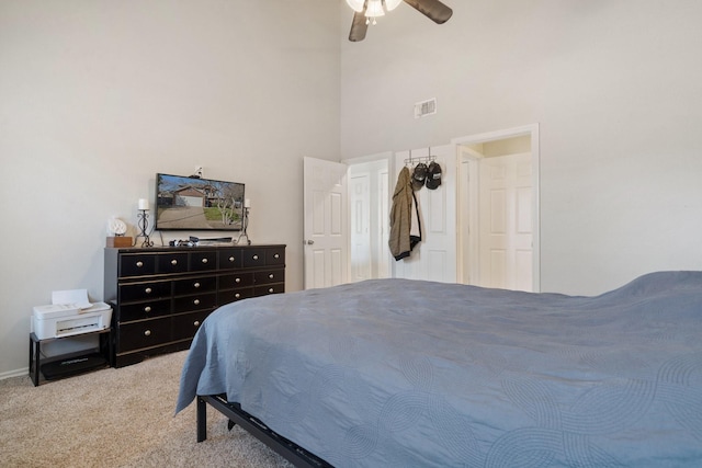 bedroom featuring a towering ceiling, light colored carpet, and ceiling fan