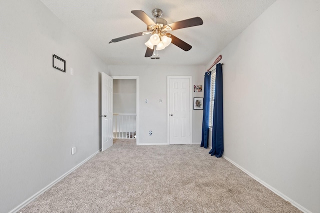 unfurnished bedroom with ceiling fan, light colored carpet, and a textured ceiling