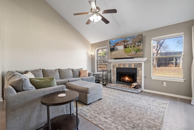 living room with dark wood-type flooring, ceiling fan, a fireplace, and high vaulted ceiling