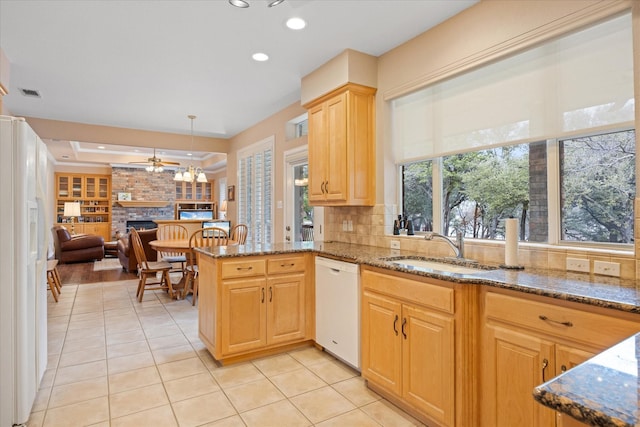 kitchen featuring sink, kitchen peninsula, decorative light fixtures, white appliances, and a fireplace