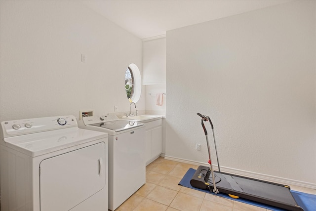 clothes washing area with washer and clothes dryer, cabinets, light tile patterned floors, and sink