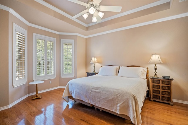 bedroom featuring a raised ceiling, ceiling fan, crown molding, and light hardwood / wood-style flooring