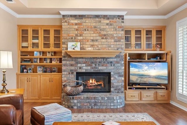 living room with a fireplace, light hardwood / wood-style flooring, a healthy amount of sunlight, and crown molding