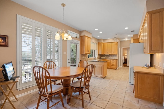 tiled dining room featuring ceiling fan with notable chandelier and sink