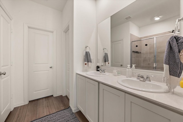 bathroom featuring hardwood / wood-style flooring, vanity, and a shower with shower door