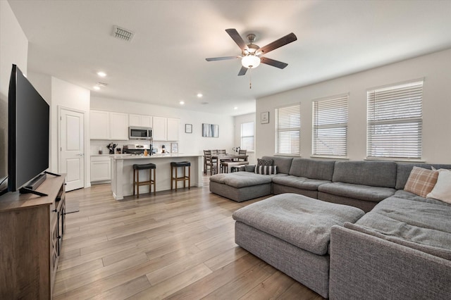 living room with light hardwood / wood-style flooring and ceiling fan