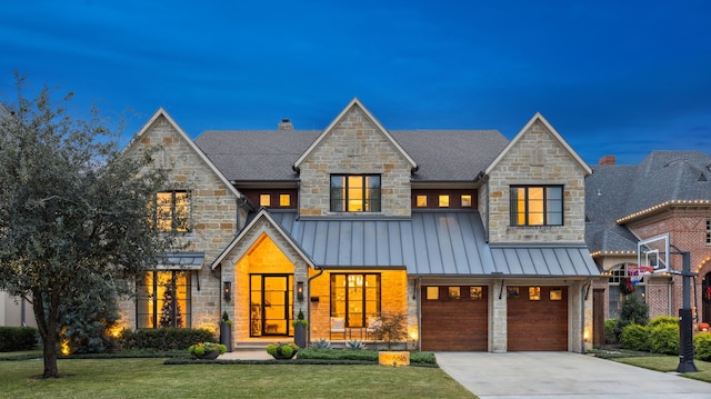 view of front of property with metal roof, concrete driveway, a lawn, a standing seam roof, and a chimney