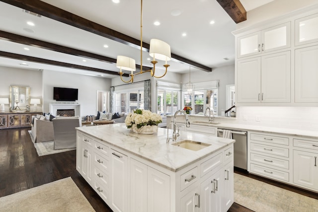 kitchen featuring a fireplace, a notable chandelier, stainless steel dishwasher, open floor plan, and a sink