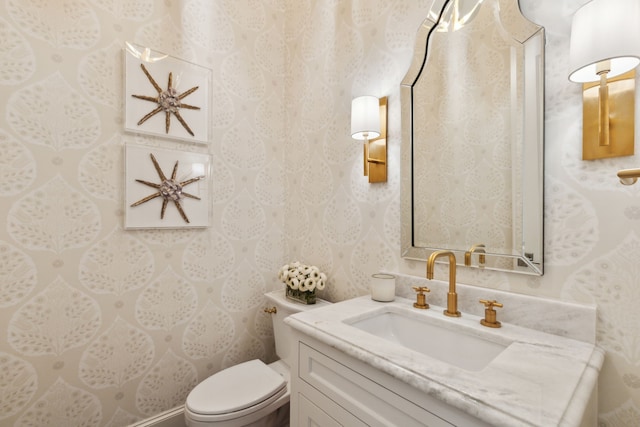 half bath with vanity, toilet, and wallpapered walls