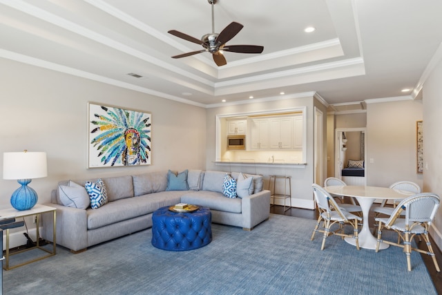 living room featuring ceiling fan, visible vents, a raised ceiling, and crown molding