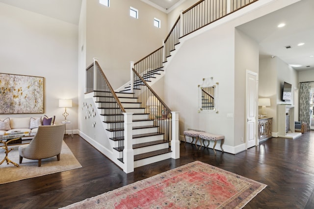 stairs with parquet floors, crown molding, and a towering ceiling