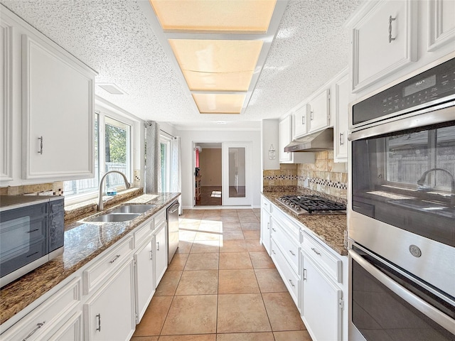 kitchen with dark stone counters, white cabinets, sink, appliances with stainless steel finishes, and light tile patterned flooring