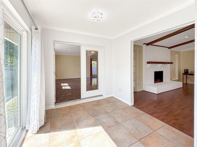 spare room with light tile patterned floors, a fireplace, ornamental molding, and a textured ceiling